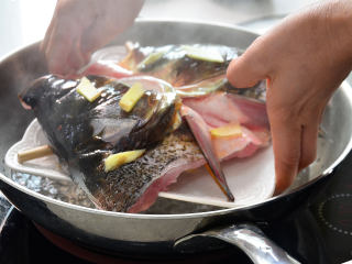 鲜美剁椒鱼头,锅加蒸架开火水烧开后把鱼头放入.大火蒸三分钟，取出来将碗里蒸出来的血水倒掉，去掉垫在底下的筷子，将拌好的辣酱料均匀的铺在鱼头上，入锅大火蒸6分钟