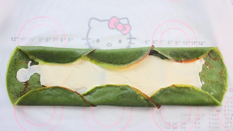 那一抹毛巾卷的绿,将饼边依次向内折叠，这样可以避免奶油漏出