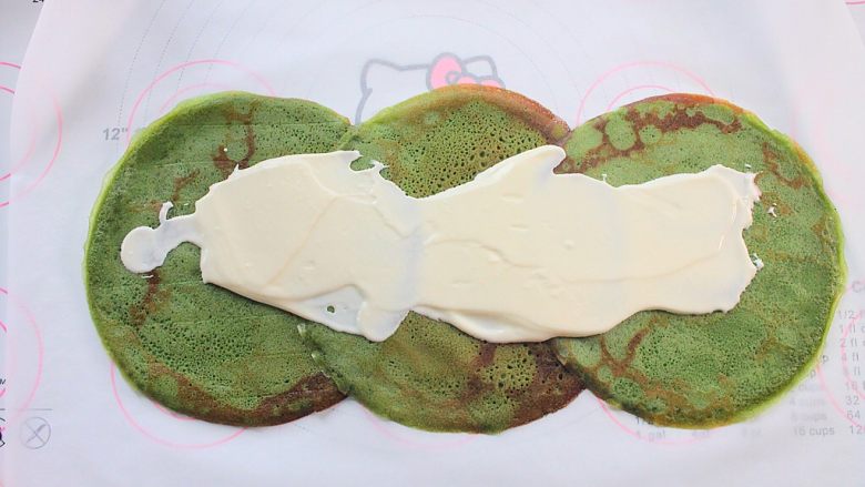 那一抹毛巾卷的绿, 将奶油涂抹在3块铺在油纸上的抹茶煎饼（图的形状像李白）