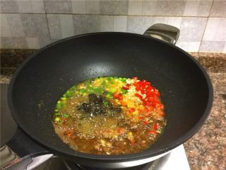 泡椒豆豉干烧鱼,放入小葱、豆豉、泡椒、泡姜和大蒜颗粒翻炒10秒。