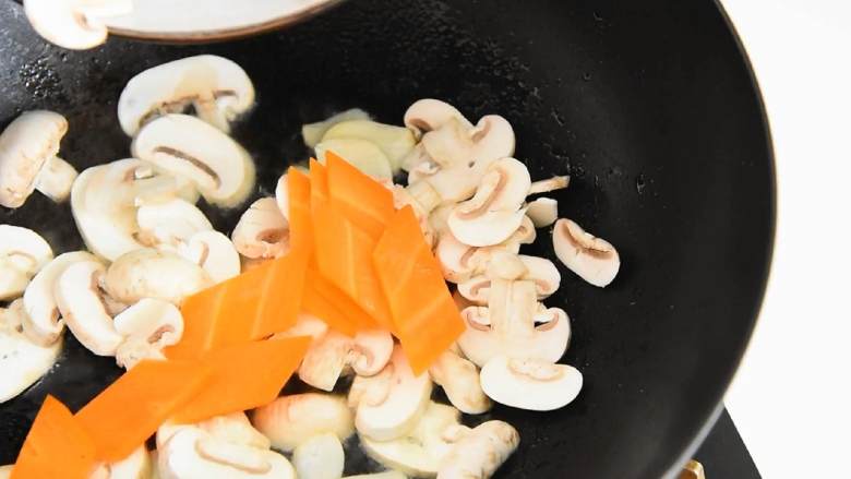 色彩缤纷的西兰花胡萝卜炒蘑菇，颜色丰富，营养也丰富,放入蘑菇、胡萝卜、翻炒至断生。