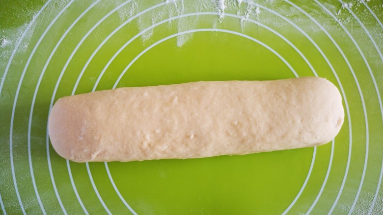 快手早餐   红糖小馒头,在揉面垫上撒上少许干面粉后将醒好的面团揉匀并搓成条状(如图)