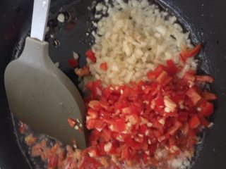 腌黄瓜,锅里倒油烧热，放进入红尖椒粒和大蒜粒，翻炒出香辣味。
