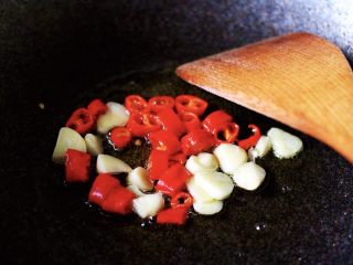 快手正餐  秋葵爆猪大肠,热锅加入花生油烧热后，放入大蒜片和红尖椒爆出香味后；