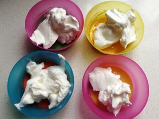 戚风棒棒糖蛋糕,接下来把打发好的蛋白霜，按先前一样的比例加入到四份蛋黄糊中，即原色蛋糊加约20克蛋白霜，彩色蛋糊加约30克蛋白霜。
