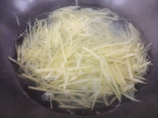 土豆丝拌洋葱丝,然后把土豆丝放在水里焯一下。