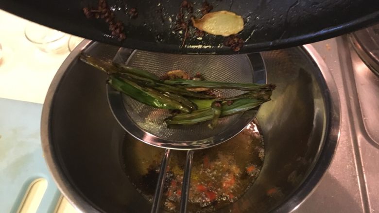 怪味口水鸡,用滤网将炒香的菜油加入大碗里，浸泡1分钟