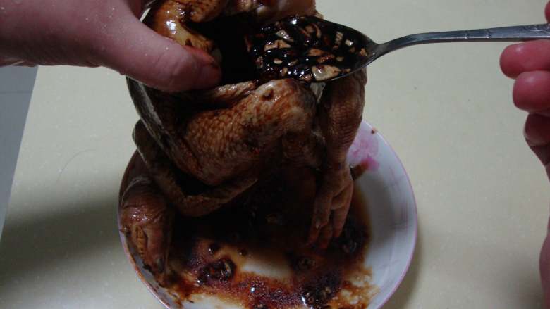 吉祥如意：金牌蒜香鸡,调好的酱料抹到鸡的身上，剩下的全部灌入鸡腹中，把鸡的爪子塞入肚子中
