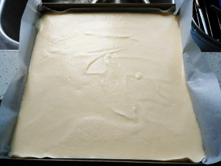 椰蓉蜂蜜蛋糕卷,倒入铺了油纸的烤盘中，抹平表面，用力震几下