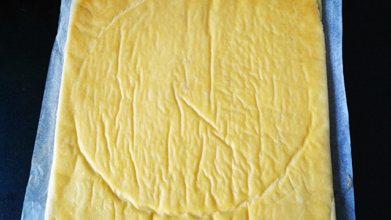 椰蓉蜂蜜蛋糕卷,稍凉倒扣在一张油纸上，撕开表面油纸