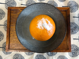 宝宝爱吃的香橙蒸蛋,将一个橙，用刀把五分之一部分切掉。