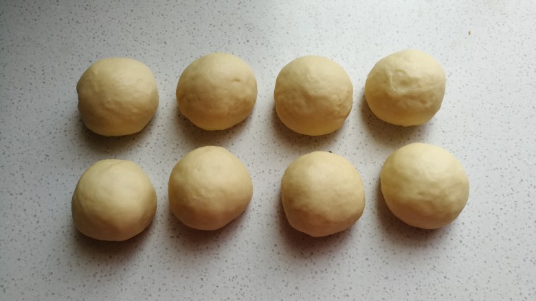 椰蓉炸面包,发酵好的面团取出挤压揉搓排气，然后分成均匀的八个剂子滚圆，盖保鲜膜静置醒发十分钟左右。
