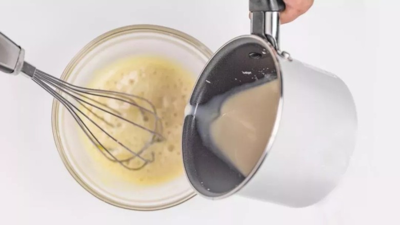 珍珠奶茶慕斯,将温度降至60°左右红茶奶液缓慢倒入蛋黄液中，不停搅拌。