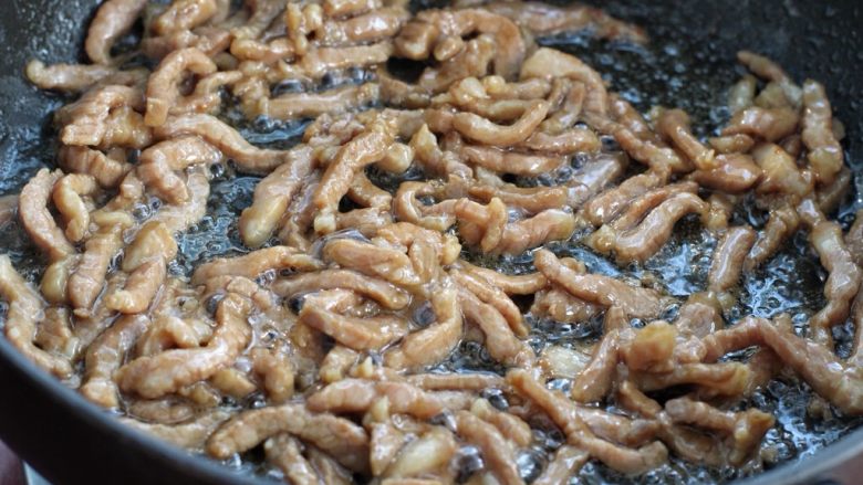 豆角丝炒肉,锅中倒适量食用油烧热，放入腌制好的肉丝滑炒至变色断生状态盛出