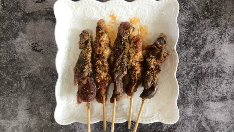 孜然猪肉串,煎锅中火烧的很热，放入黄油融化。把肉串放入煎锅中，用中小火煎烤肉串。