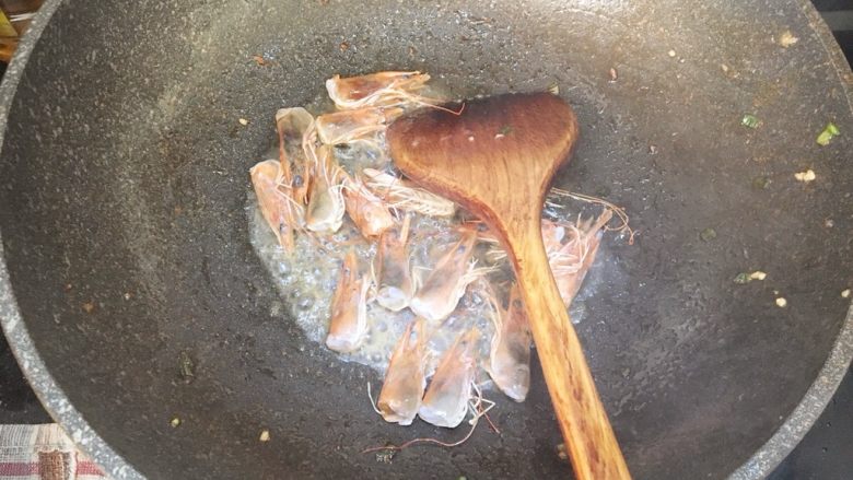 鲜虾蘑菇炒面,锅内倒入多一些的油，把虾头放入炒出虾膏，用锅铲按压虾头挤出虾膏