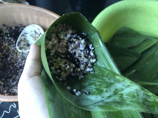 迷你杂粮粽,先取一粒黑豆放在底部，再舀入杂粮，装至“漏斗”三分之二满。