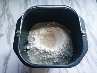#我的厨房必杀技#布里欧修吐司,除黄油外的食材全部加入面包桶，先倒入牛奶，糖全蛋液，再加入高筋面粉，低筋面粉，最后再面粉的顶端挖个洞，把酵母粉加入洞洞里，再用周边的面粉盖起来。