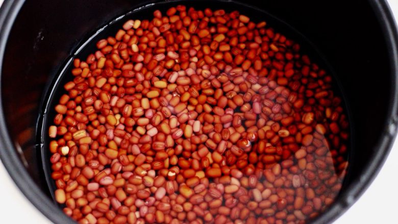 椰浆红豆芋圆水果捞,把浸泡好的红豆放入电饭煲中、加入适量清水