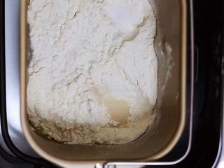 酸奶吐司,把奶粉、砂糖、全蛋液和牛奶倒入面包桶里，再加入高筋面粉后，盐和酵母不要放到一个地方，然后用面粉盖上；