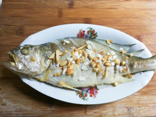 金银蒜黄鱼,剩下的一半蒜粒放入热锅凉油里面煎出香味，变成浅黄，一起淋在黄鱼表面蒜粒上