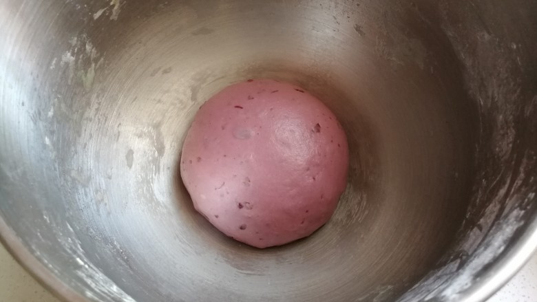 淡奶油紫薯蜜豆吐司,把揉均匀的蜜豆紫薯面团放入搅拌桶内盖保鲜膜发酵。