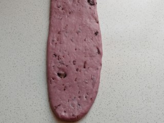 淡奶油紫薯蜜豆吐司,卷好的面团再次用擀面杖擀成长的长舌状。