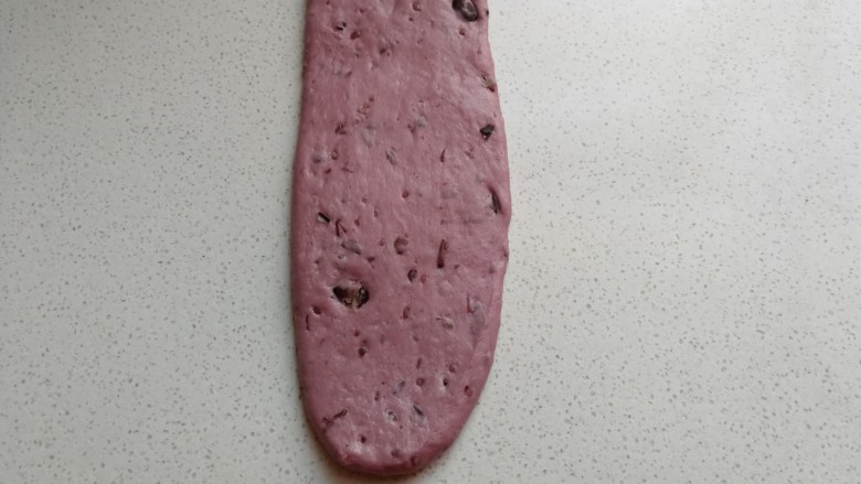 淡奶油紫薯蜜豆吐司,卷好的面团再次用擀面杖擀成长的长舌状。