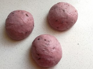淡奶油紫薯蜜豆吐司,发酵好的面团取出来挤压排气，然后分成均匀的三份滚圆，再盖上保鲜膜静置醒发十分钟左右。