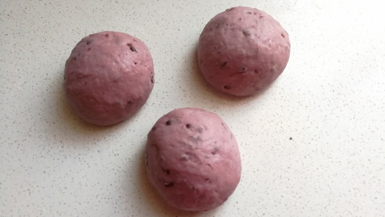 淡奶油紫薯蜜豆吐司,发酵好的面团取出来挤压排气，然后分成均匀的三份滚圆，再盖上保鲜膜静置醒发十分钟左右。