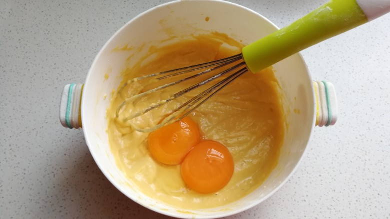 蔓越莓南瓜戚风蛋糕,蛋清蛋黄分离，加入两颗蛋黄，用手抽同上方法继续搅打均匀。