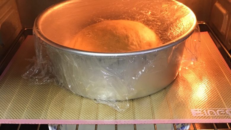 南瓜泥吐司面包,整理滚圆，放入模具盖上保鲜膜，放烤箱发酵60分钟，底部放热水帮助发酵。
