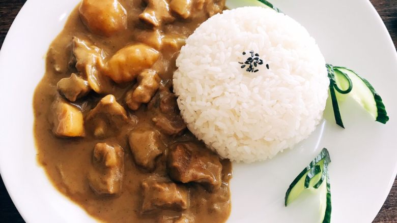 椰香咖喱牛腩,煮好的米饭盛入小碗倒扣于盘中，旁边舀上咖喱牛腩酱