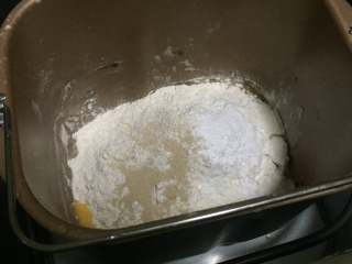 萌萌哒小狗面包,接下来，我们在面包机内，依次放入鸡蛋液、食用油、南瓜泥和糖。
然后，再放入干性材料面粉和酵母，接着开始启动机器进行揉面，大约15分钟即可。揉面结束后我们需要将面团进行第一次发酵，时间约为半个小时。