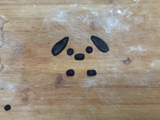萌萌哒小狗面包,接下来，我们将巧克力的面团平均分割成若干小份，每份约为1克左右，分别做出狗狗的耳朵，眼睛，鼻子，以及爪子。
