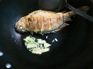 烧黄鱼,黄鱼推到锅边，将锅稍微斜着将油留下来，放入葱姜煎出香味