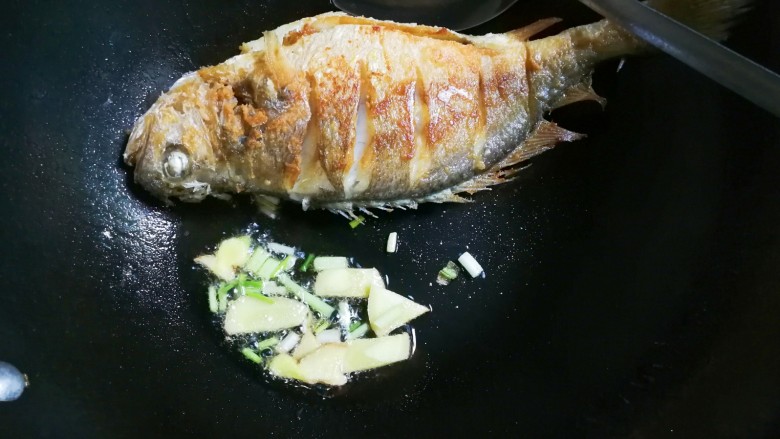 烧黄鱼,黄鱼推到锅边，将锅稍微斜着将油留下来，放入葱姜煎出香味