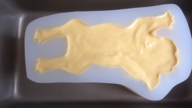 3D沙皮狗慕斯蛋糕,将芒果慕斯糊缓慢倒入沙皮狗模具里（模具需要提前几分钟从冷冻层取出来），利用小汤匙将慕斯糊划到不易流入的脚趾等部位，最后将模具在桌面上震动几下