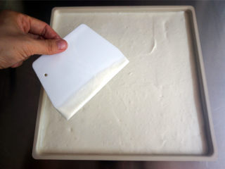 椰奶芙蓉卷,将蛋糕糊倒入烤盘，用刮板抹平表面。
