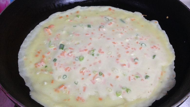 奶香胡萝卜鸡蛋饼,
摊上薄薄的一层，尽量把饼摊圆，一直保持中小火慢慢烙