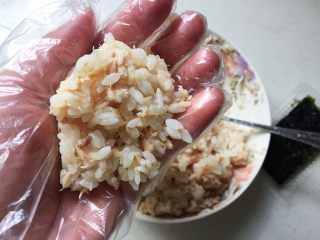 快手日式金枪鱼饭团,戴上一次性手套，取适量拌匀的米饭放在一手的掌心