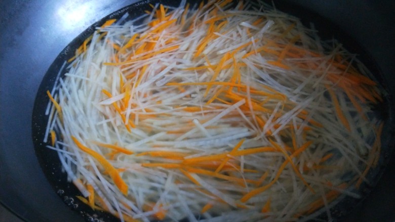 新文美食  椒香胡萝卜土豆丝,锅中放入适量水烧开，倒入土豆  胡萝卜丝煮两分钟捞出来。