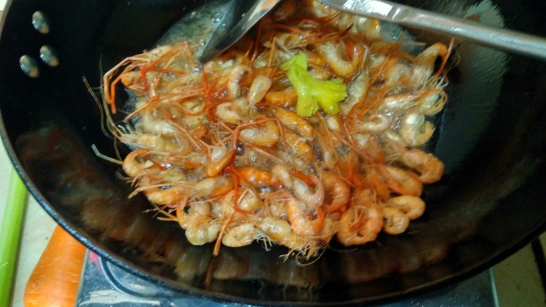 韭苔爆河虾,油热（开始冒烟）时，倒入控干水分的河虾和生姜，用锅铲轻轻翻搅均匀。