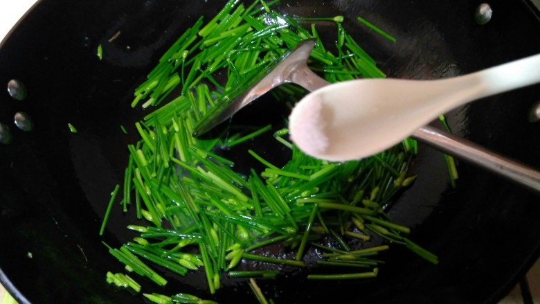韭苔爆河虾,再次开火，锅中倒入少许虾油，油热后倒入韭苔，用手洒一些清水，加入一点点盐，翻炒至七分熟。