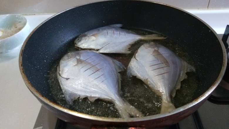 新文美食  香煎小平鱼,平台锅烧热倒入适量油，放入三条平鱼煎制。