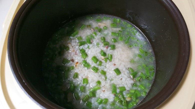 豇豆饭,将炒好的豇豆大米盛出放到电饭锅内胆里面，放入和食材平齐的热水