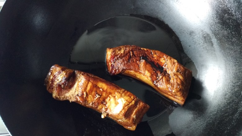 梅菜扣肉,将上色后的肉放入油锅。记住一定要在油热之前放肉，盖上锅盖。