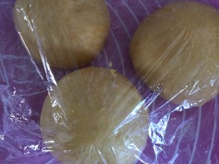 南瓜红豆吐司,面团按压排气后，平均分割成3个面团，盖保鲜膜醒发15分钟。