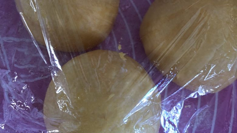 南瓜红豆吐司,面团按压排气后，平均分割成3个面团，盖保鲜膜醒发15分钟。