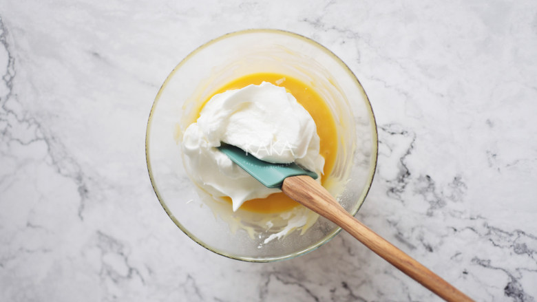 色彩斑斓的炫彩戚风蛋糕,取三分之一的蛋白霜加入到蛋黄糊中，翻拌均匀